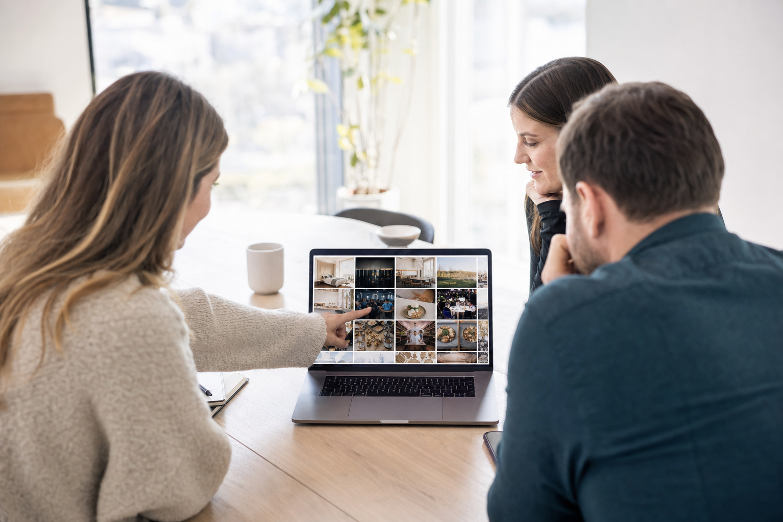 A small marketing team compares photo organization software for teams on a laptop showing a shared photo grid.